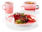 Een roze Le Creuset mok, kom en bord met steak en groenten.