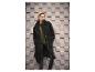 Femme en manteau teddy noir, cardigan vert et pantalon en cuir