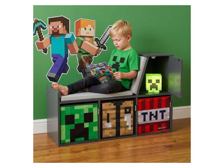 Enfant lisant sur un banc de rangement à thème de jeu vidéo, avec décoration murale et lampe.