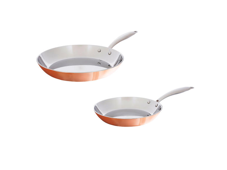 Twee koperen koekenpannen met zilveren binnenkant en metalen handvatten op een witte achtergrond.