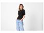 Femme en t-shirt noir côtelé et jean clair, les mains dans les poches.