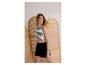 Femme en crop top rayé et short noir, posant à côté d'un paravent en rotin.