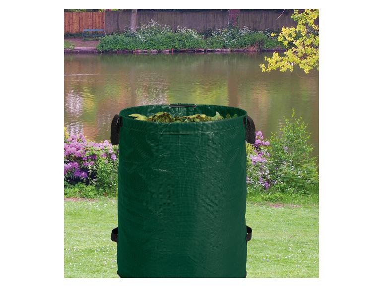 Groene tuinzak vol bladeren, met een meer en groen in de achtergrond.