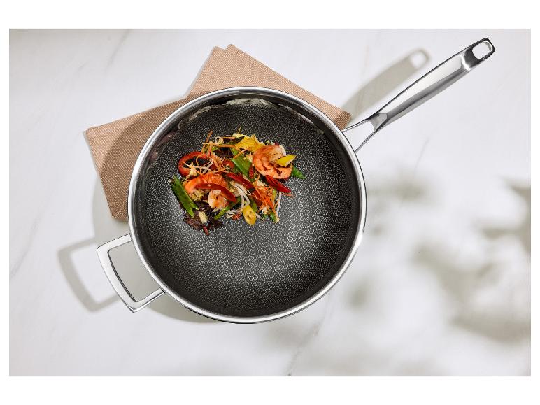 Poêle avec poignées métalliques et plat sauté aux crevettes et légumes.