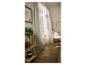 Lichte woonkamer met houten vloer, gordijnen, planten en een fauteuil.