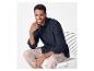 Homme en chemise bleu marine et pantalon beige assis sur une chaise blanche.