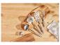 Ustensiles de cuisine en acier inoxydable, dont une spatule, une louche et un fouet, sur une planche à découper en bois.