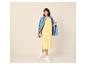 Femme en robe jaune et veste en jean bleue, souriante.