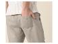 Homme en haut tricoté blanc et pantalon en lin gris clair, main dans la poche.