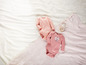 Deux bodies bébé à manches longues roses sur une couverture blanche.