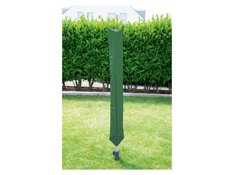 Housse de séchoir rotatif verte dans un jardin avec une haie et une maison en arrière-plan.