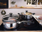 Deux casseroles Tefal avec couvercles en verre sur une plaque à induction.