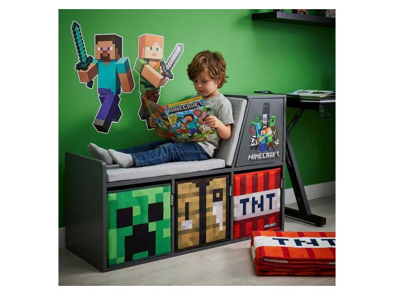 Enfant lisant une bande dessinée de jeu vidéo sur un banc de rangement à thème de jeu vidéo.