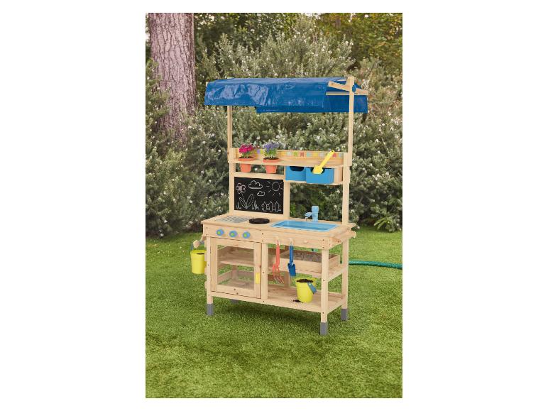 Cuisine de jeu extérieure en bois avec toit en bâche bleue, tableau noir, évier et outils de jardinage.