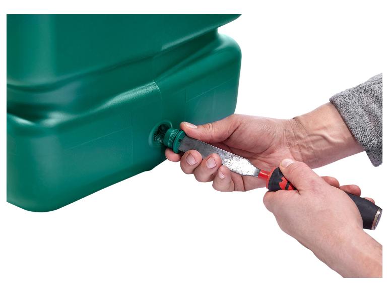 Mains installant un tuyau en plastique vert dans un réservoir de récupération avec un outil.