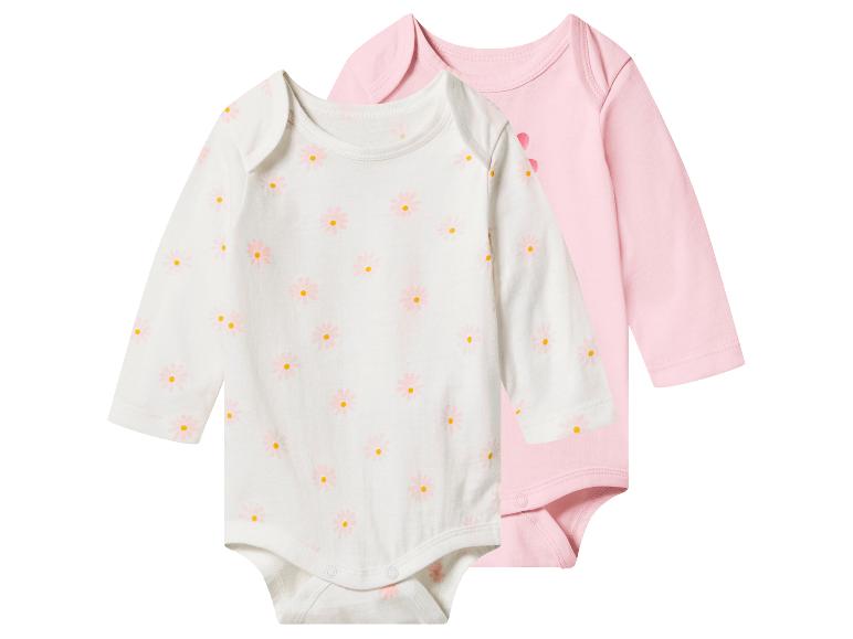 Deux bodys bébé à manches longues : un blanc à marguerites roses et un rose uni.