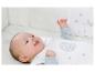 Bébé dans une gigoteuse blanche avec étoiles et lune dans un berceau.