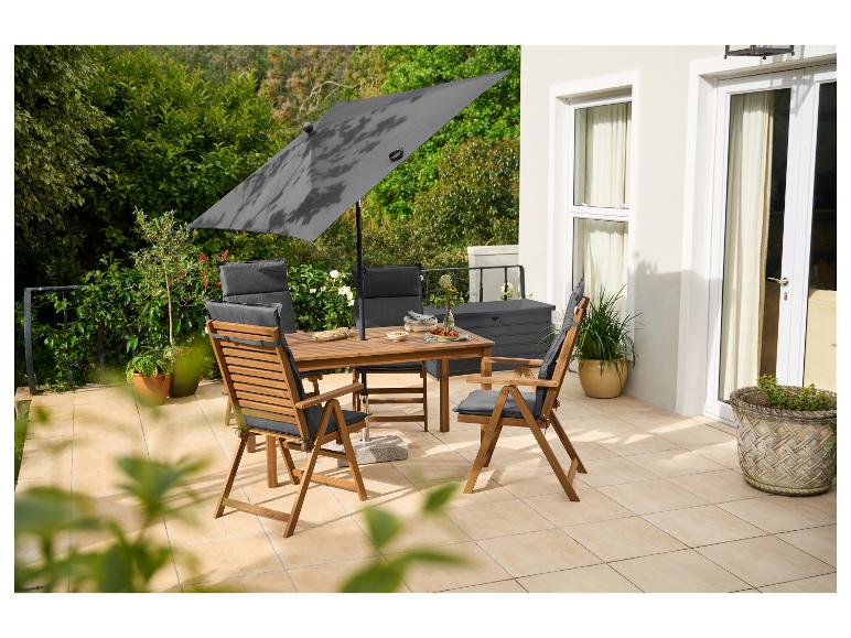 Table et chaises de jardin en bois avec parasol sur une terrasse.