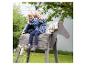 Twee kinderen spelen op een houten hobbelpaard in een tuin.