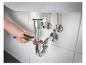 Un plombier utilise une clé à tuyauterie sous un lavabo.