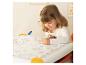 Petite fille dessinant sur un grand livre de coloriage avec un marqueur vert.