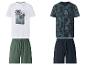 Twee sets van T-shirt en shorts: één wit T-shirt met palmbomen en groene shorts, en één donkerblauw T-shirt met tropisch patroon en donkerblauwe shorts.