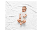 Lachende baby in een wit rompertje met krab-print op een wit kleed.
