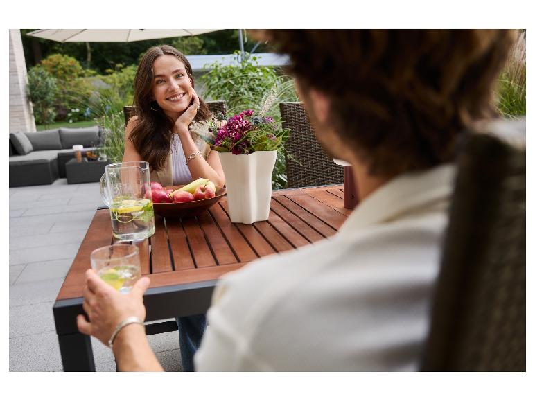Paar geniet van een verfrissend drankje en fruit op een houten terras.