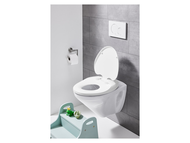 Een toilet met een kinderzitje, een toiletrolhouder en een toiletpot.