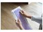 Des mains tenant une serpillière pour nettoyer le sol.