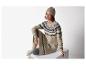 Femme en long pull Fair Isle et bonnet beige, assise.