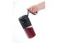 Main tenant un mixeur portable SilverCrest avec un smoothie rouge.