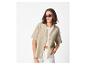 Vrouw in een beige linnen overhemd, witte crop top en witte shorts.