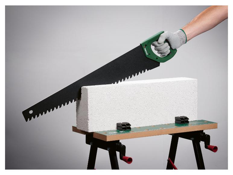 Une scie à main Parkside coupant un bloc de béton sur un établi.