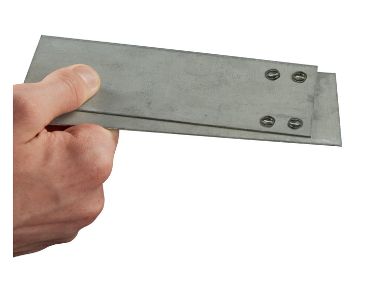Hand houdt twee metalen platen vast met schroeven.