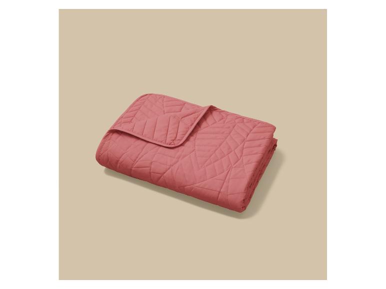 Couverture ou jeté de lit rose matelassé avec motif géométrique.