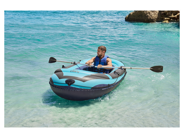 Een man peddelt in een blauwe opblaasboot van Crivit op het water.