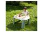 Jeune enfant jouant avec une table de sable et d'eau à l'extérieur sur l'herbe.