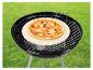 Pizza op pizzasteen op houtskoolbarbecue op gazon.