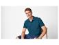 Homme en polo turquoise et short en jean, assis sur une chaise.
