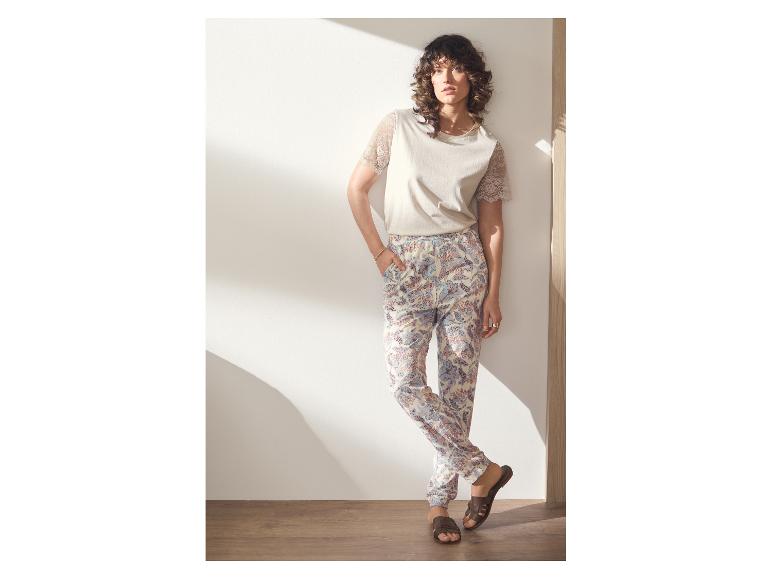 Femme en t-shirt beige à manches en dentelle et pantalon imprimé.