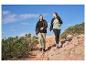 Deux personnes en randonnée avec des vestes, t-shirts et pantalons de plein air sur un sentier rocheux.