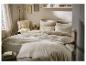 Lichte slaapkamer met beige bed, houten nachtkastje en plank met decoraties.