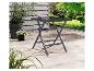 Grijze opvouwbare tuintafel op een terras met planten en een groene tuin op de achtergrond.
