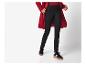 Femme en manteau rouge, pull rouge et pantalon noir, avec des baskets noires.