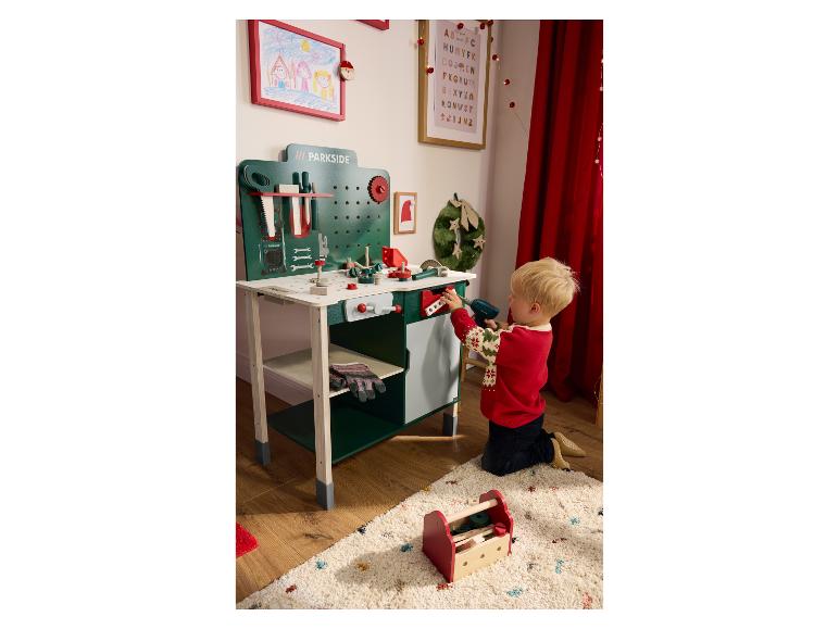 Un enfant joue avec un établi Parkside et un ensemble d'outils sur un tapis.