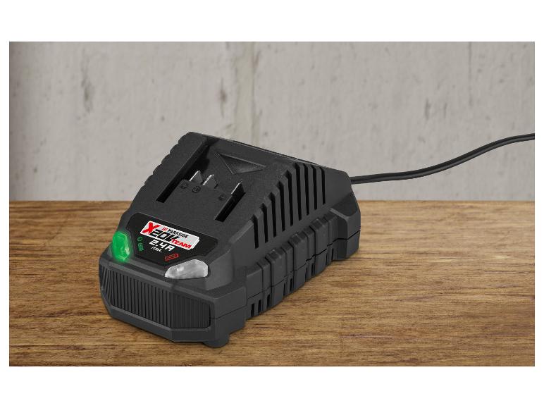 Zwarte acculader met groen licht op een houten tafel.