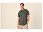 Jeune homme en polo vert foncé avec des détails rayés et un short beige.