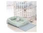 Wit babybedje met pluchen speelgoed en een mintgroene wieg op een blauw vloerkleed.