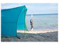 Een blauwe tent van Outwell op het strand, met een vrouw die ernaast loopt.